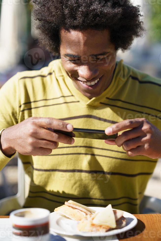 preto cubano tirando uma foto com seu smartphone para um lanche