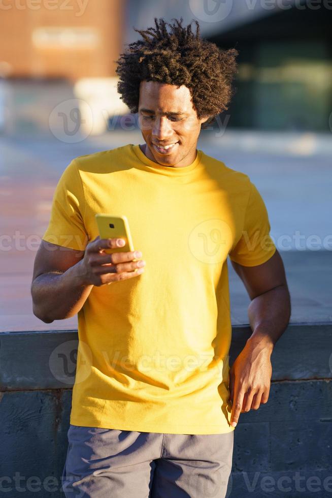 homem negro consultando seu smartphone enquanto descansava do treino. foto
