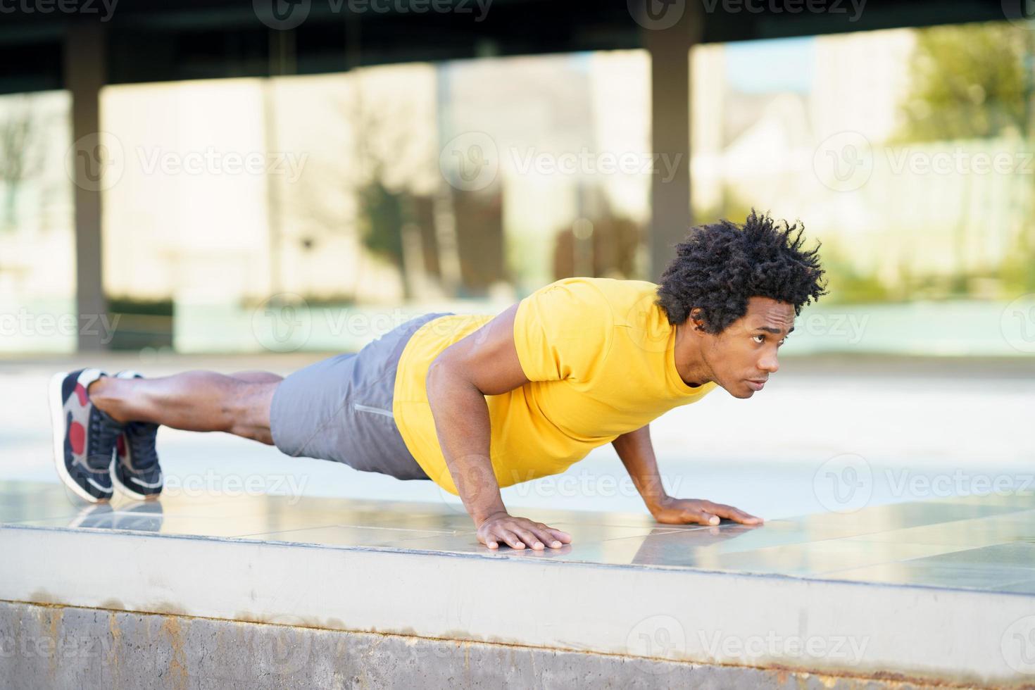 homem negro fazendo exercício de mergulho de tríceps no banco da rua da cidade. foto