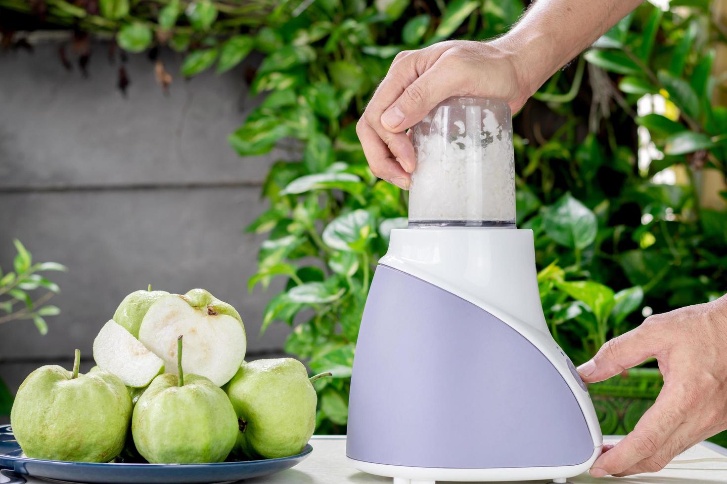 usando um liquidificador elétrico para fazer suco de goiaba fresco foto