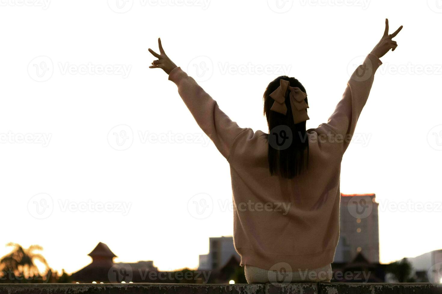 silhueta do jovem mulher levantando dela mãos acima dela cabeça e fazer mão placa com dois elevado dedos este significa vitória e encorajamento. encorajamento conceito com vitória e liberdade símbolos foto