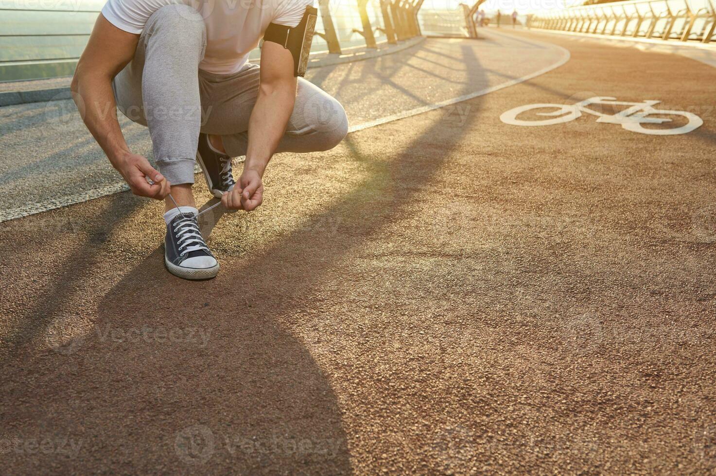 atleta corredor amarrar cadarços, pronto para correndo. raios solares queda em uma cidade ponte esteira. cardio dar certo, ao ar livre Esportes treinamento, movimento, resistência e saudável estilo de vida conceito. fechar-se. foto