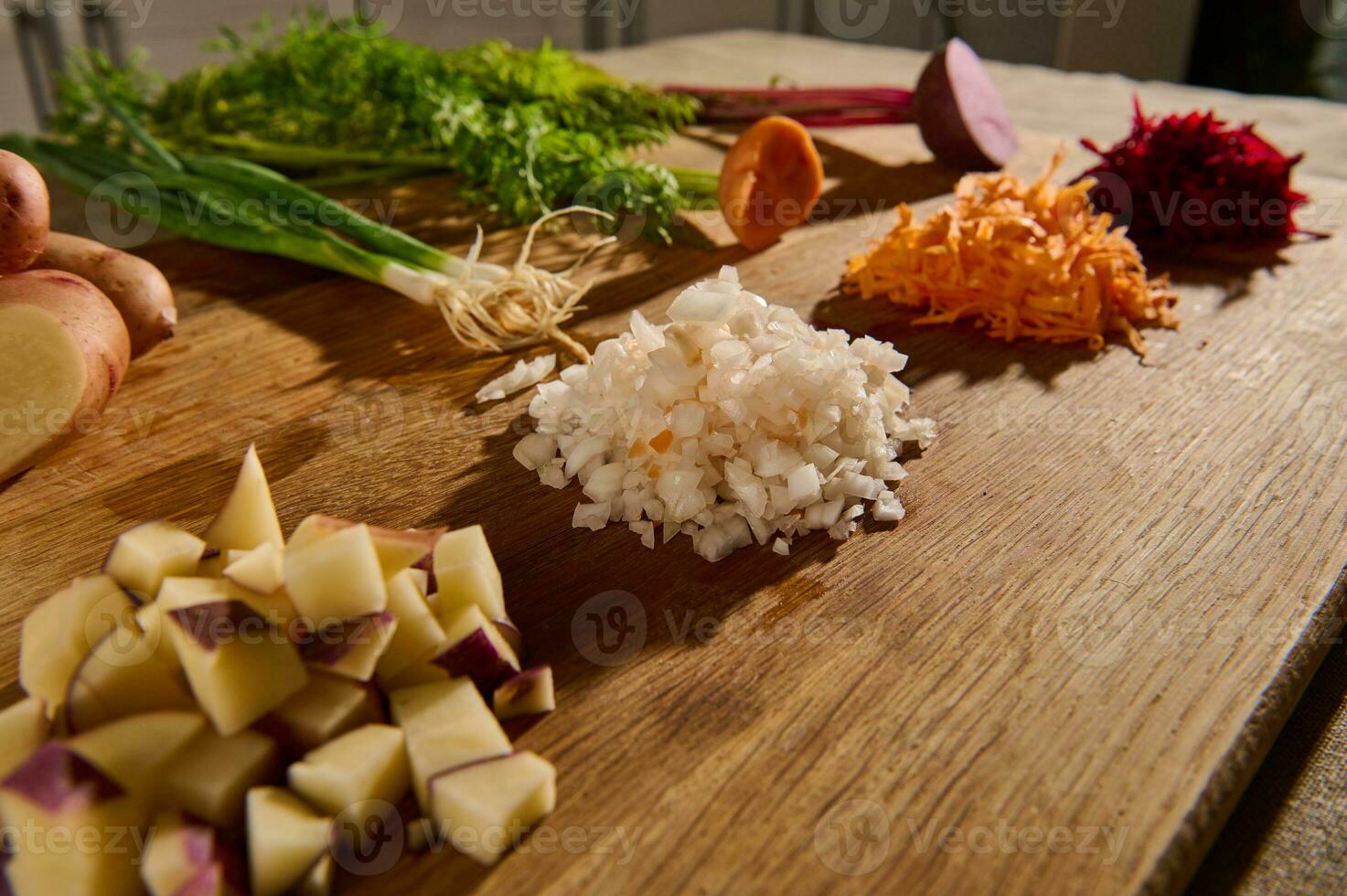 trincado beterraba, cenoura, cebola e cubos do cortar batata em uma de madeira borda com metades do legumes com verde folhas e raízes em a fundo. fechar-se. Comida fundo foto