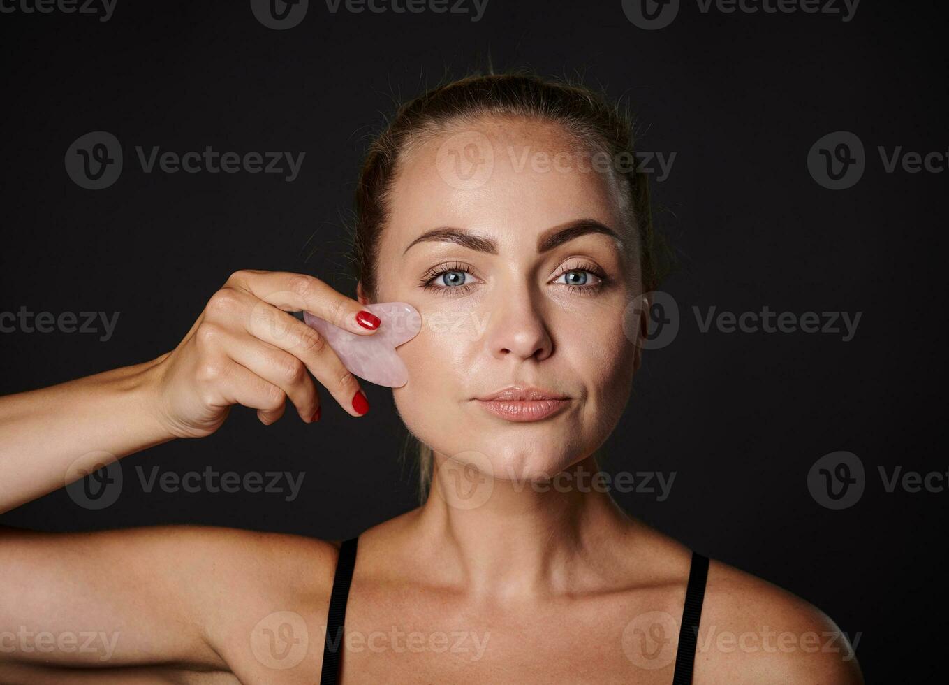 estúdio tiro do uma bonita mulher fazendo uma linfático drenagem facial massagem com uma jade pedra gua sha massager. beleza spa tratamento. fechar-se. anti-envelhecimento, alisamento, rejuvenescimento beleza terapia foto