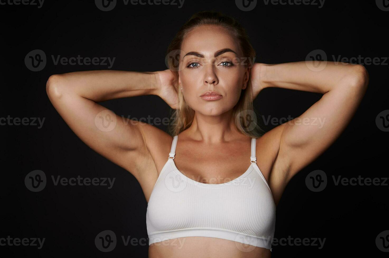 lindo Loiras caucasiano mulher dentro branco roupa íntima com confiança olhando às Câmera posando contra Preto fundo com cópia de de Anúncios espaço foto