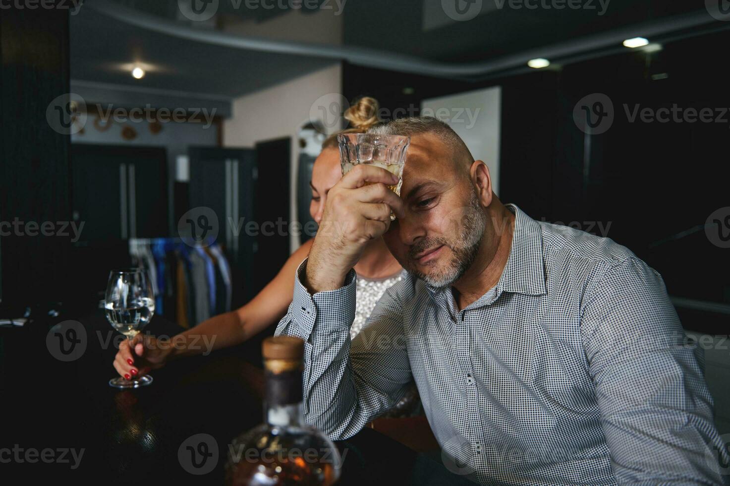 bonito meio envelhecido caucasiano homem dentro casual terno bebendo álcool, sentado às uma Barra contador topo perto dele namorada às casa foto