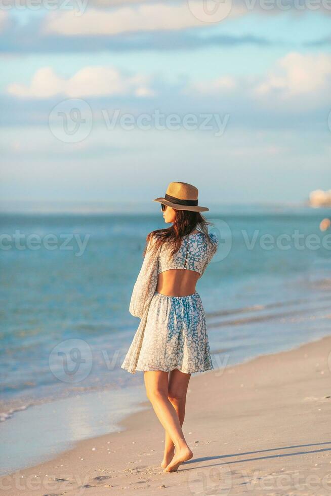 jovem feliz mulher em a de praia apreciar dela verão período de férias. lindo mulher dentro chapéu é feliz e calma dentro dela fique em a de praia foto