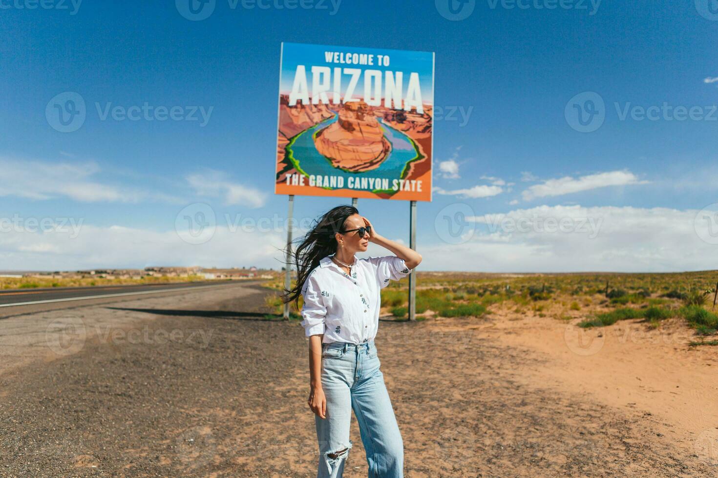 lindo mulher em dela viagem para a EUA em a fundo do bem-vinda para Arizona Estado fronteira placa certo dentro a paje desfiladeiro, EUA foto