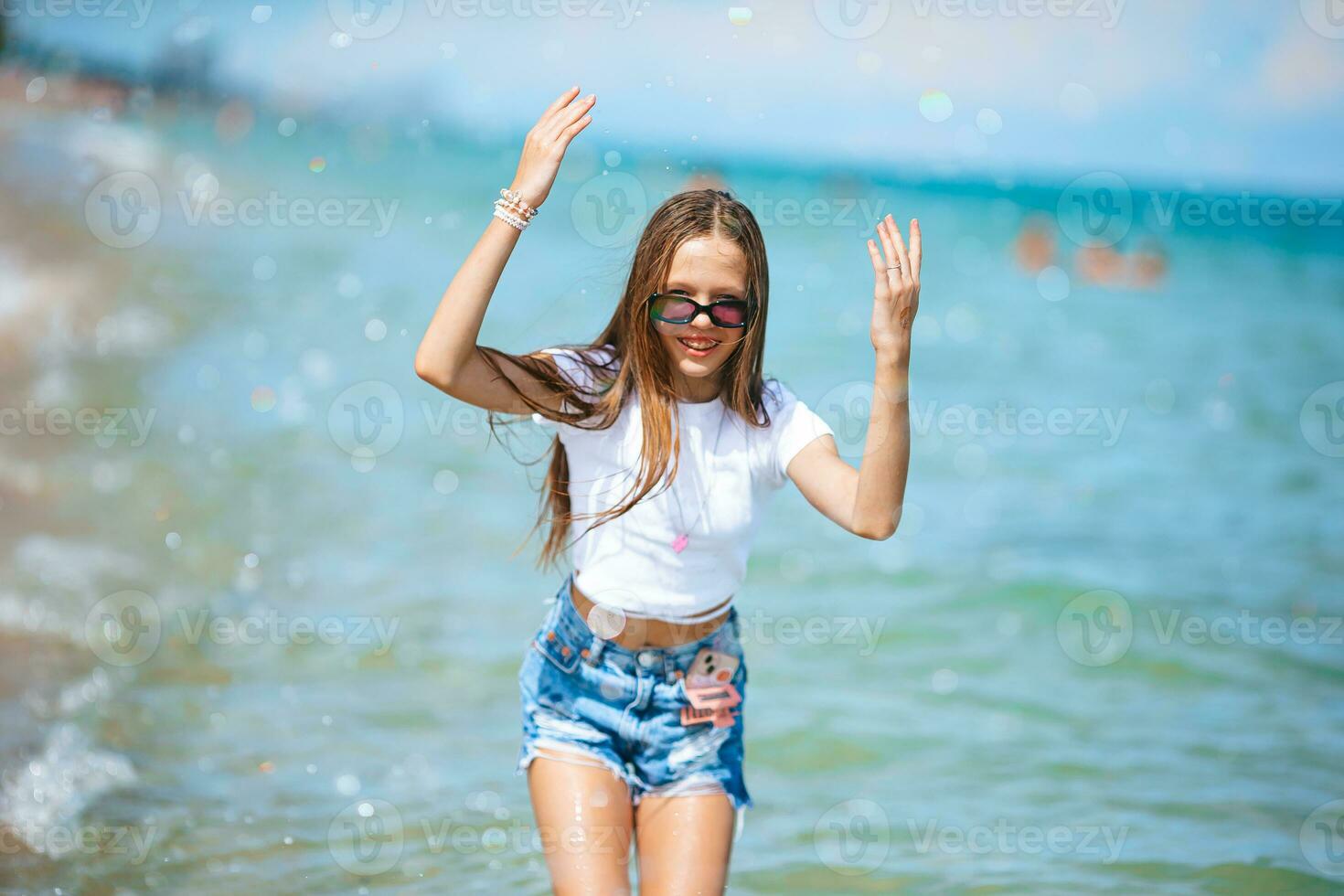 menina feliz espirrando na água azul-turquesa foto