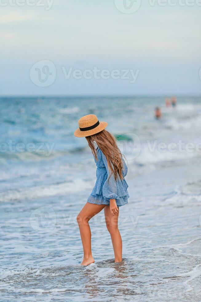 lindo adolescente menina em tropical Beira Mar caminhando às raso água e tendo Diversão foto