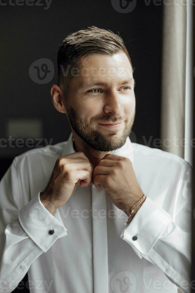 a à moda noivo vestidos, prepara para a Casamento cerimônia. ampla retrato. Maravilhoso interior dentro a manhã claro. a do noivo manhã foto