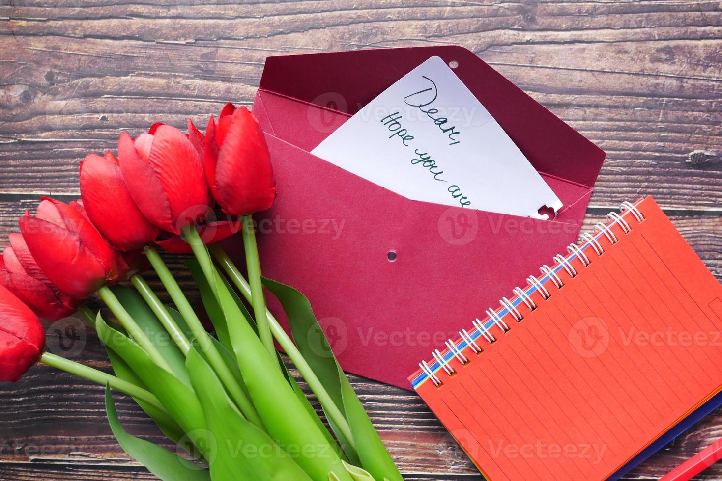 envelope, carta e flor de tulipa na mesa foto