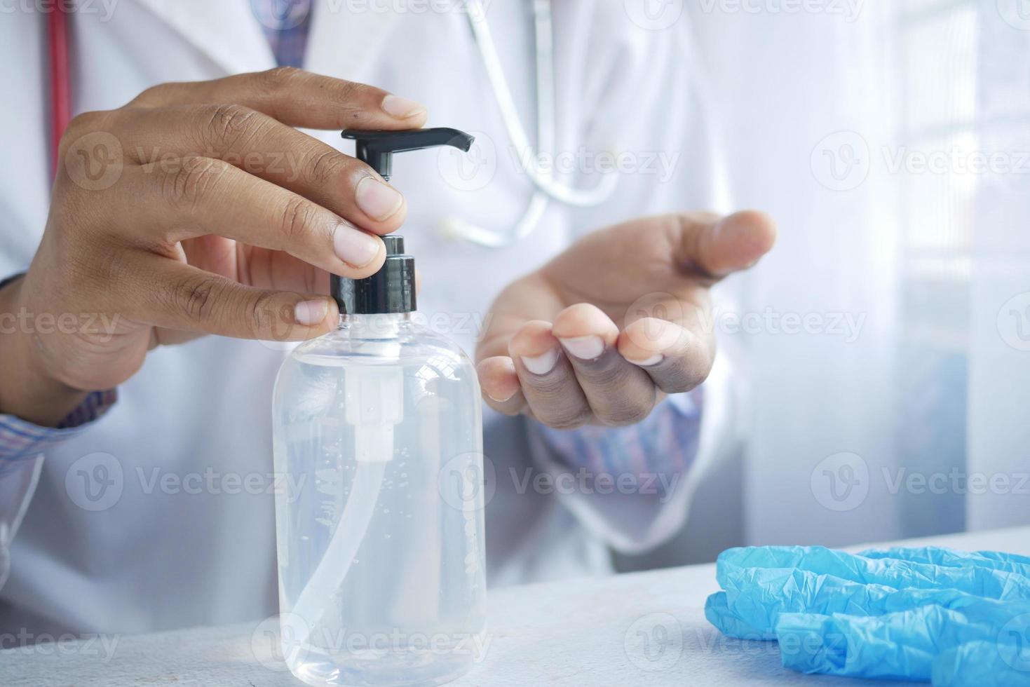 close-up da mão do médico usando gel desinfetante foto
