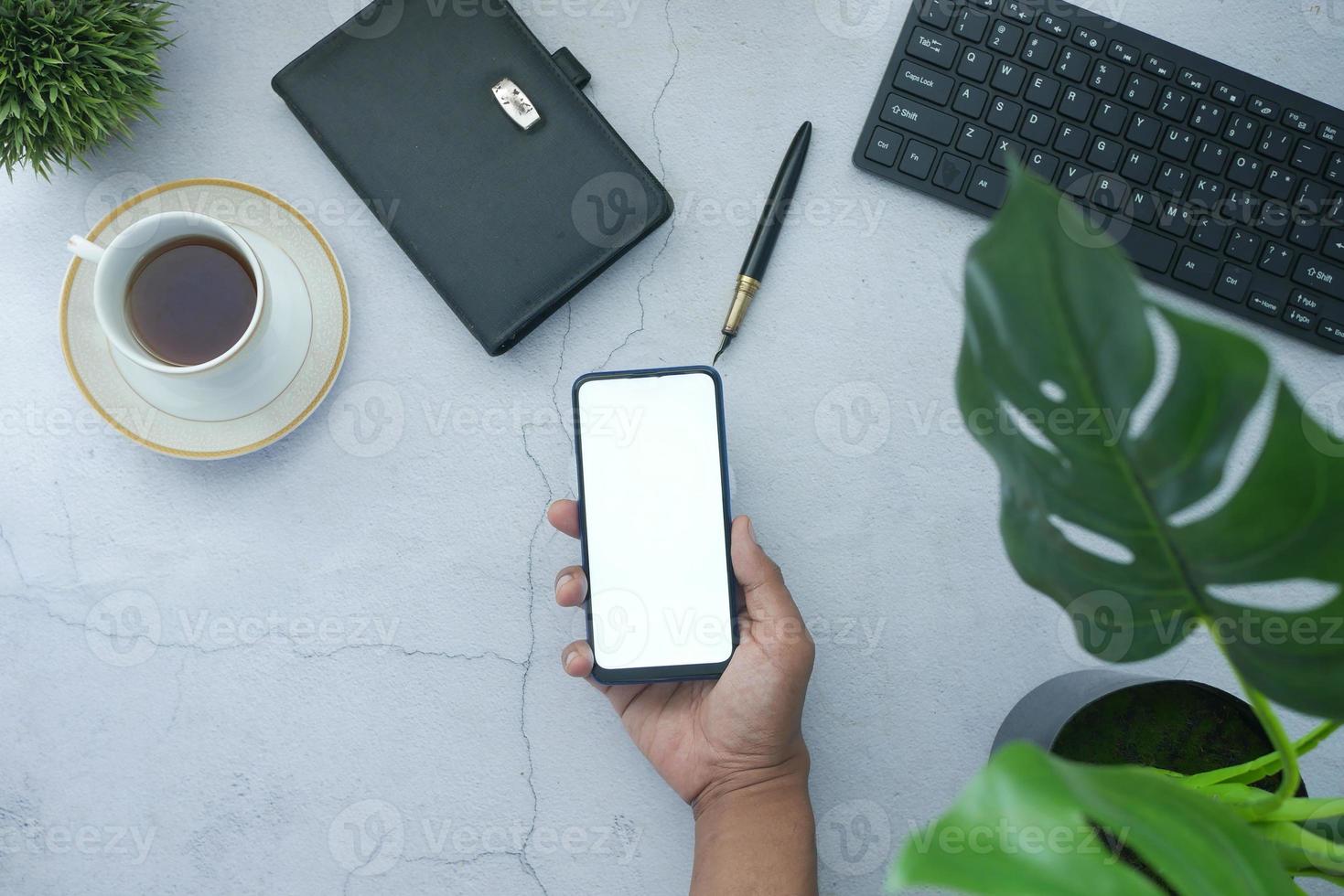 vista superior da mão de um homem segurando um telefone inteligente com tela vazia foto
