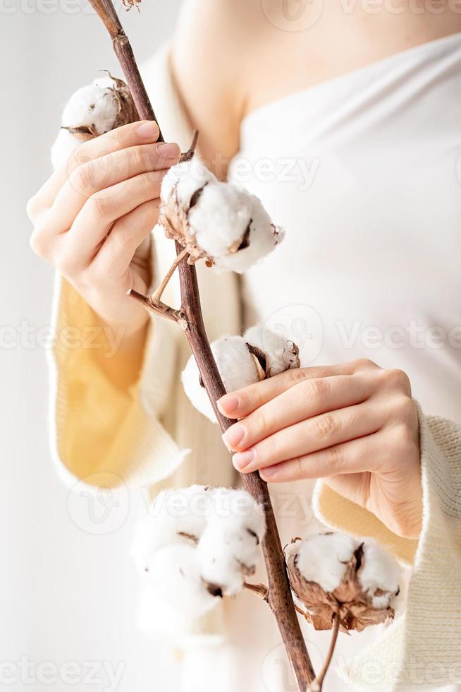 linda mulher com as mãos segurando um ramo de flores de algodão foto