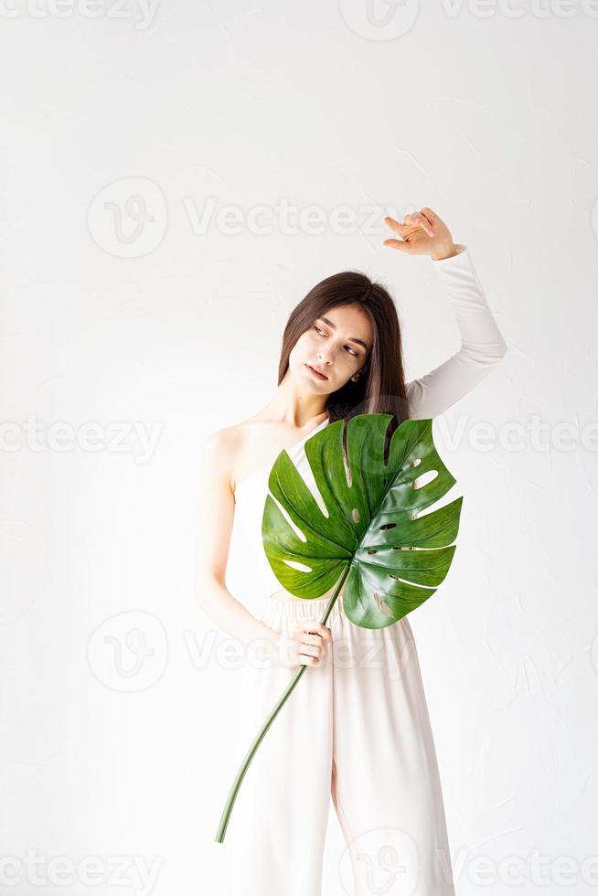 Mulher bonita e feliz em roupas aconchegantes segurando uma folha de monstro verde foto