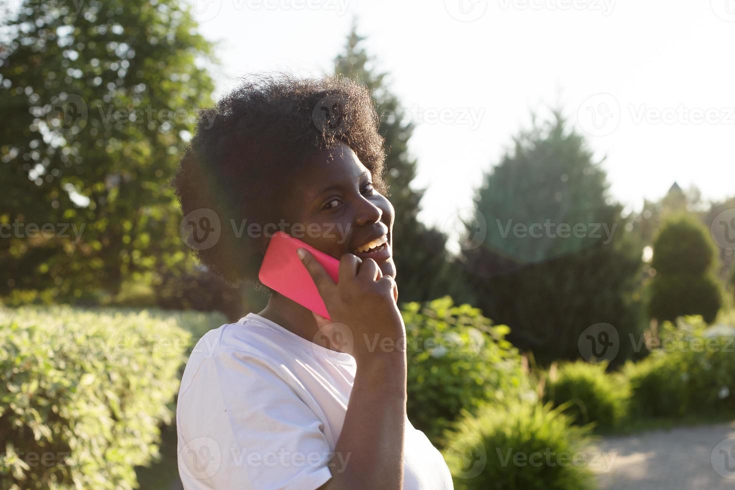 mulher afro-americana feliz com um telefone na rua no verão foto