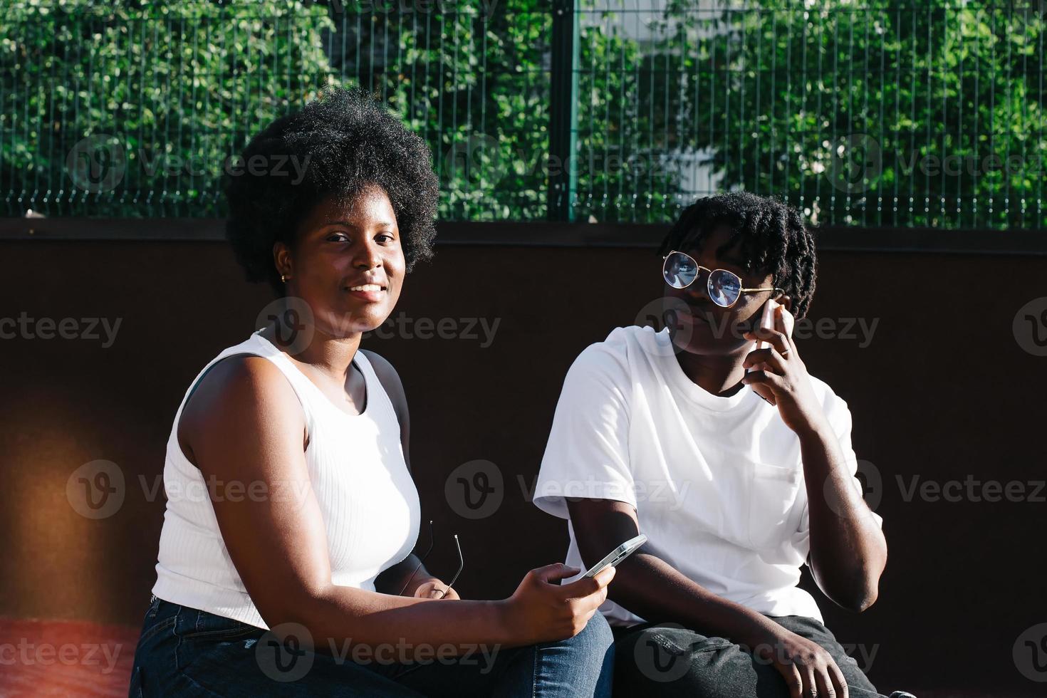 duas mulheres afro-americanas felizes se comunicam e riem na rua foto