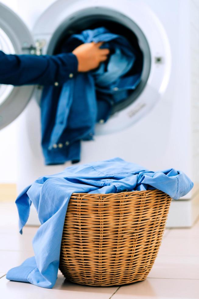 feche a máquina de lavar e roupas na cesta foto