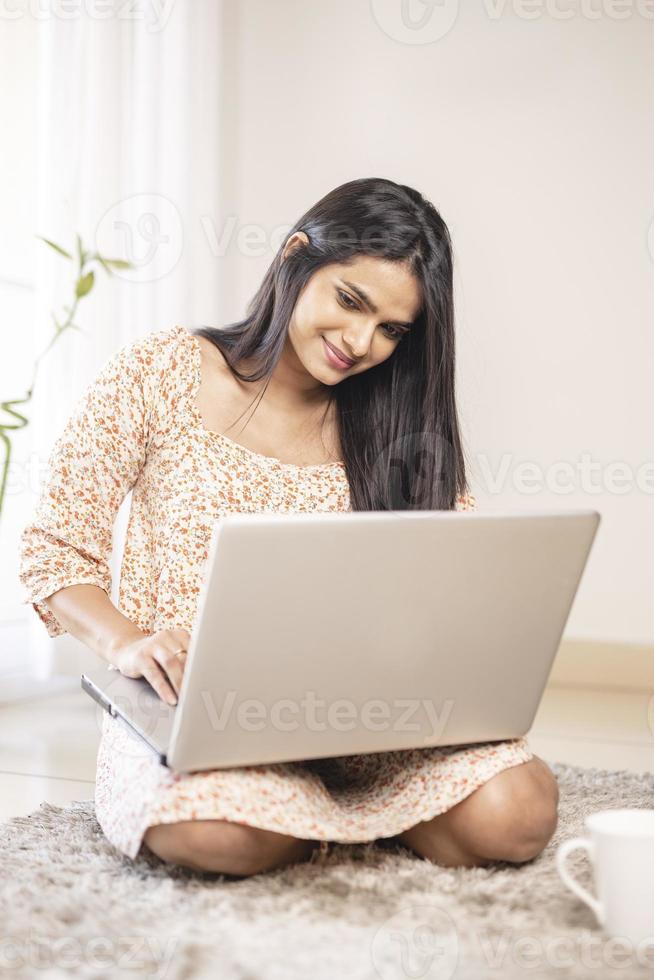 linda jovem indiana usando laptop em casa foto