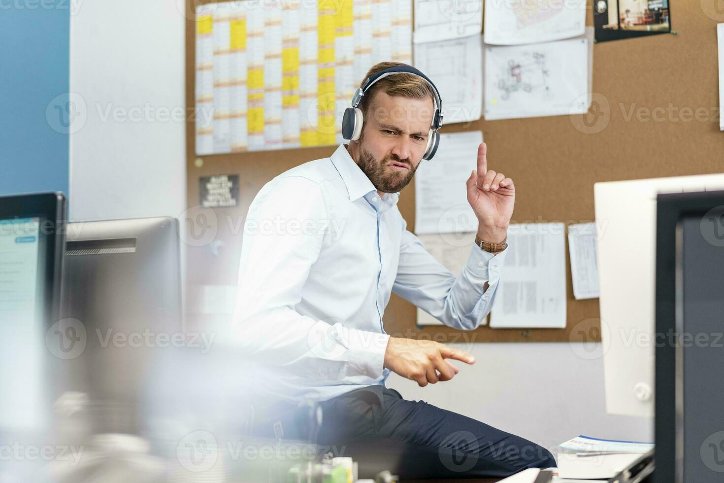 homem de negocios ouvindo para música com fones de ouvido dentro escritório foto