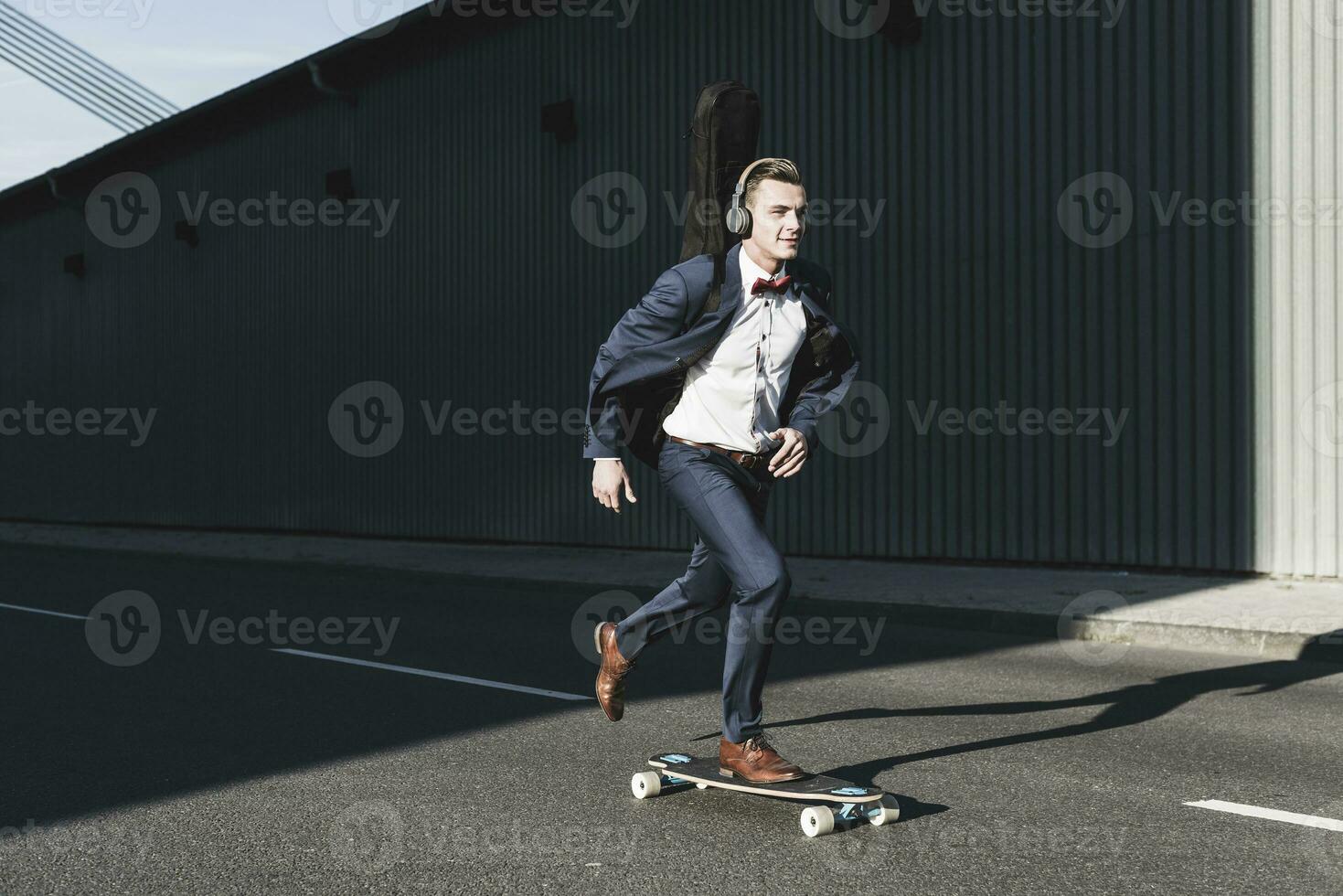 jovem homem com guitarra caso equitação skate em a rua foto