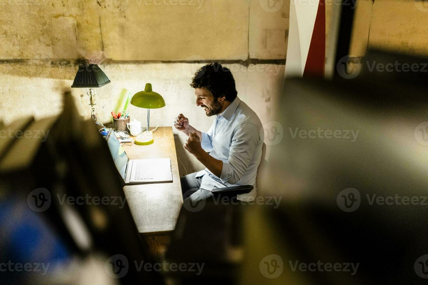 torcendo homem de negocios usando computador portátil em mesa dentro a Sombrio foto