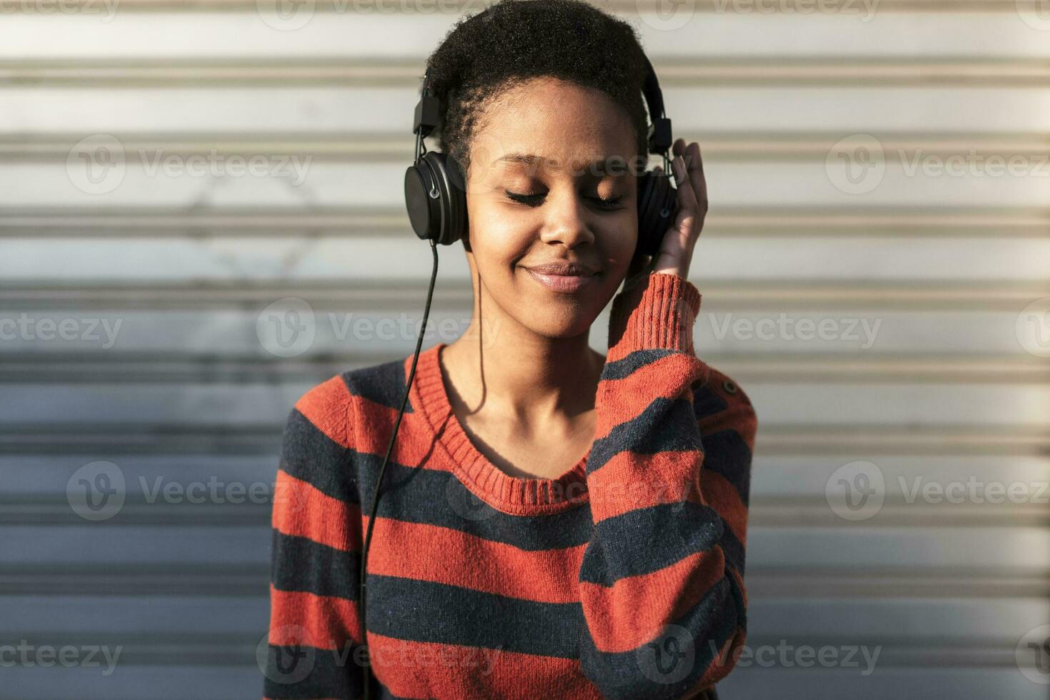 retrato do sorridente jovem mulher ouvindo música com fones de ouvido foto