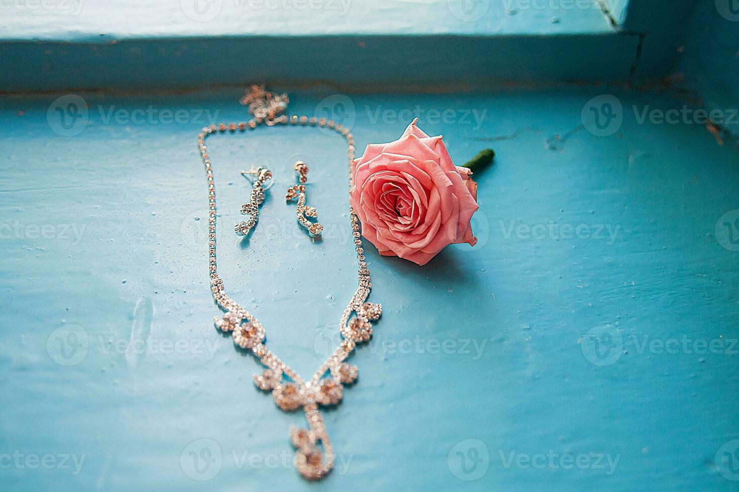 rosa elegante com colar e brincos em um azul foto