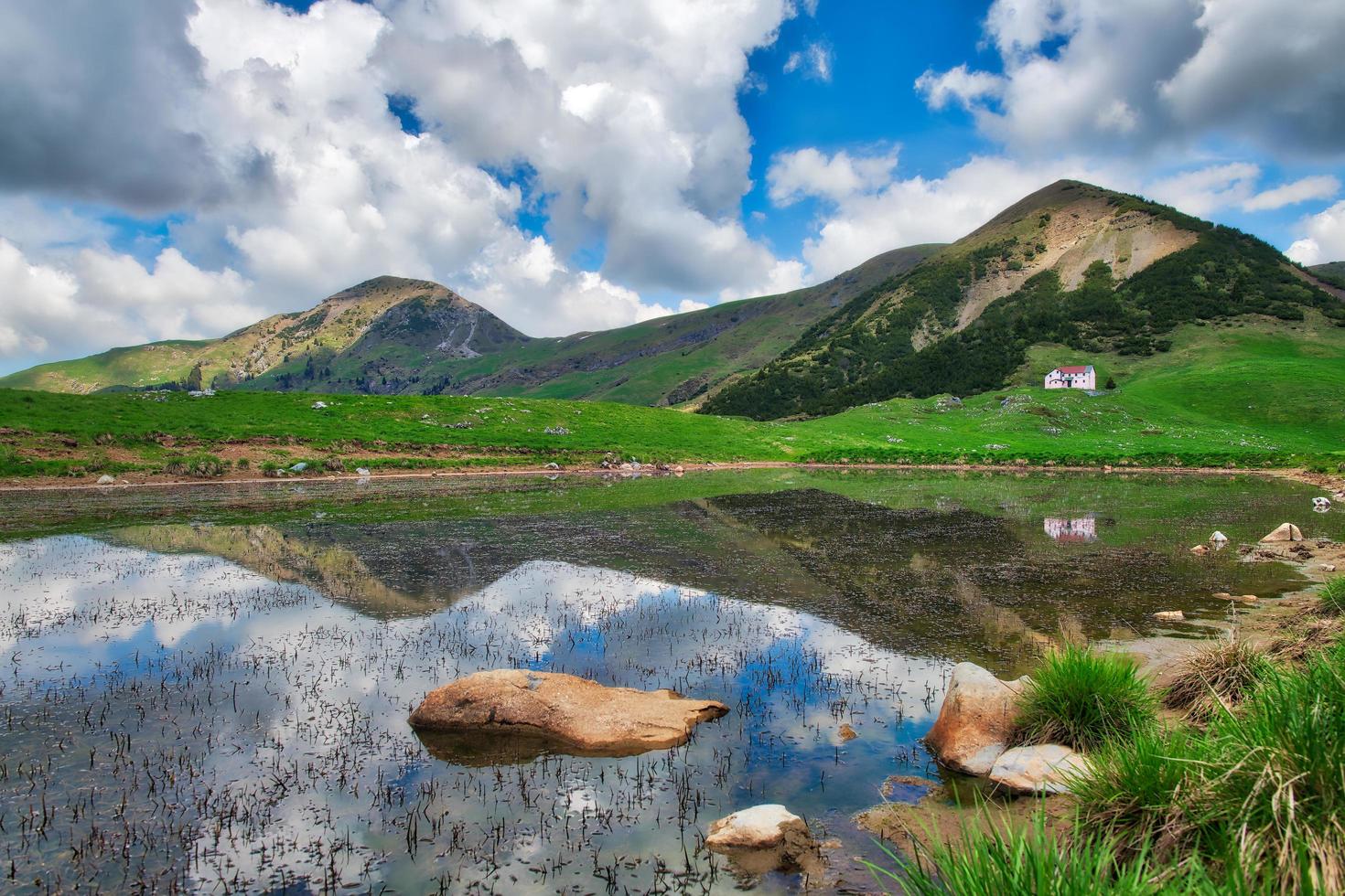 pequeno lago alpino com montanhas refletidas é uma cabana alpina foto