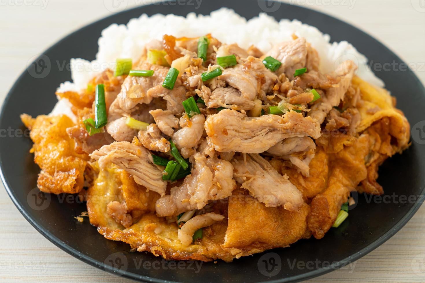 Carne de porco frita com alho e ovo coberto com arroz - comida asiática foto