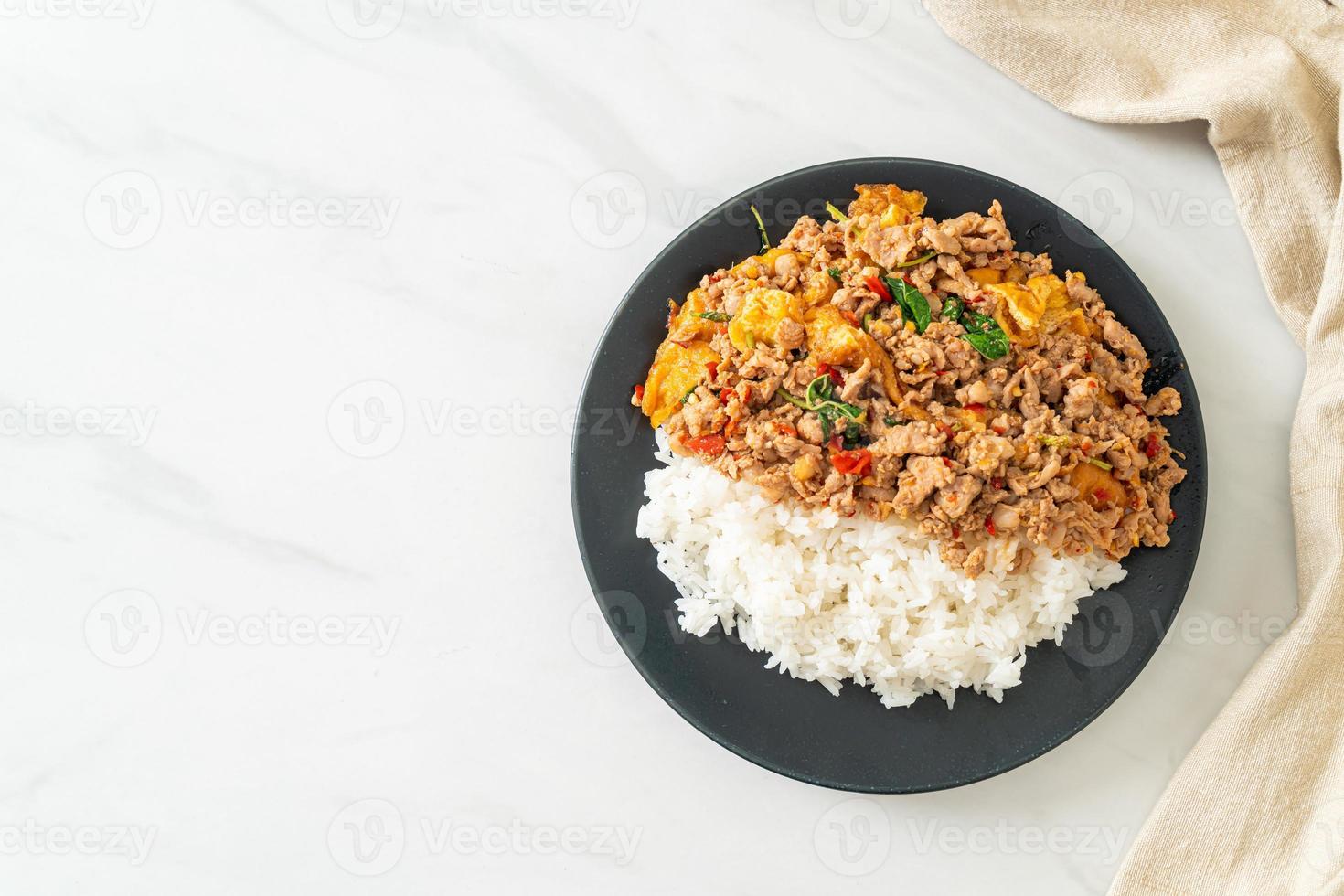 Carne de porco picada frita com manjericão e ovo coberto com arroz - comida asiática foto