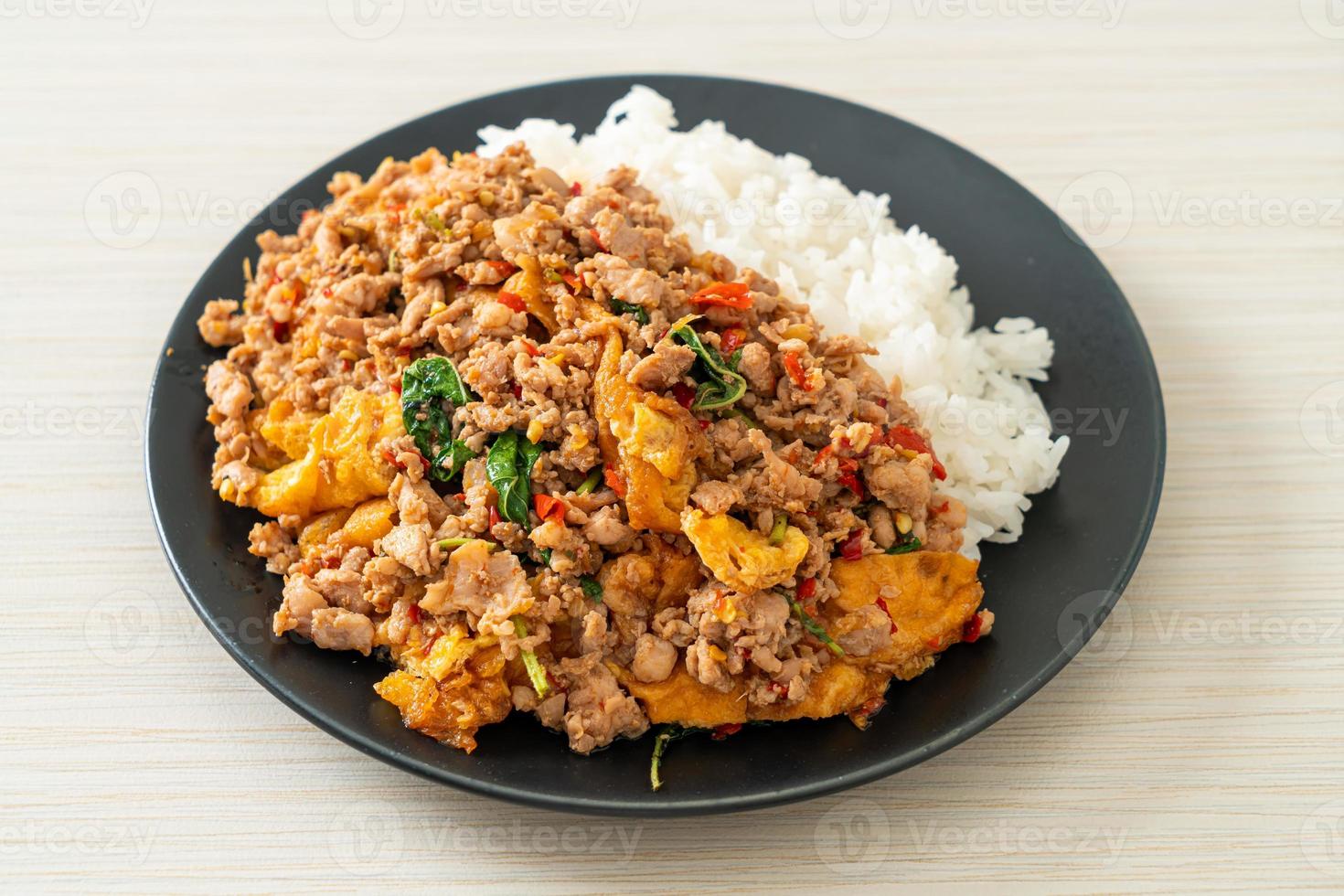 Carne de porco picada frita com manjericão e ovo coberto com arroz - comida asiática foto