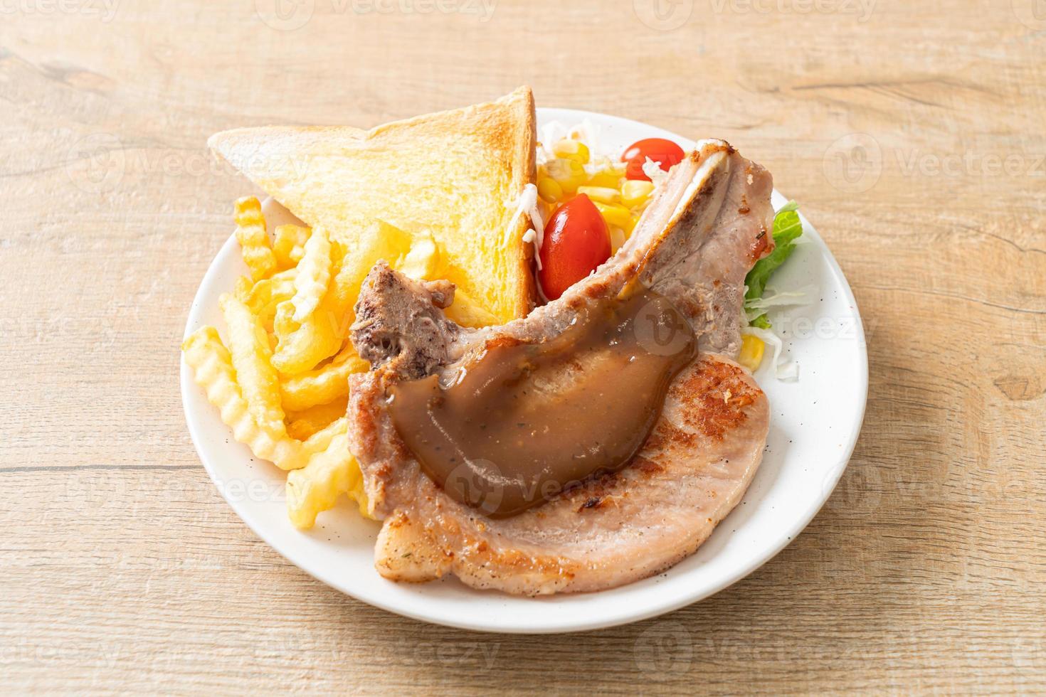 bife de costeleta de porco com batatas fritas e mini salada em prato branco foto