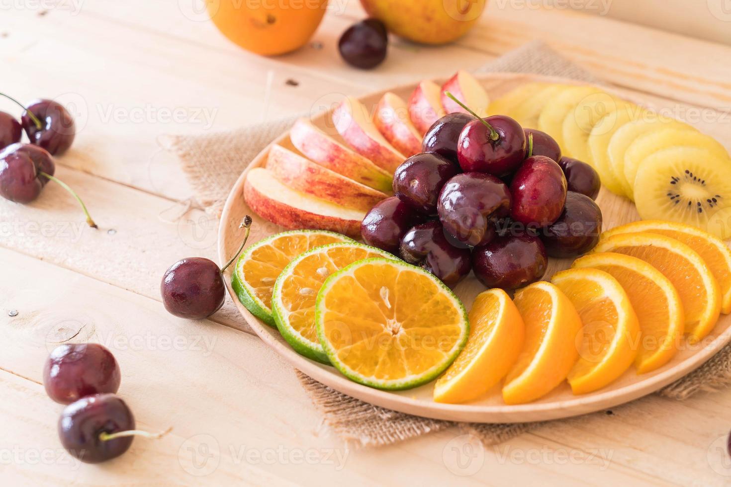 Misto de frutas fatiadas em tigela de madeira foto