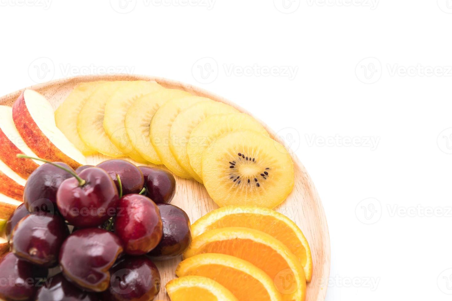 Misto de frutas fatiadas em tigela de madeira foto