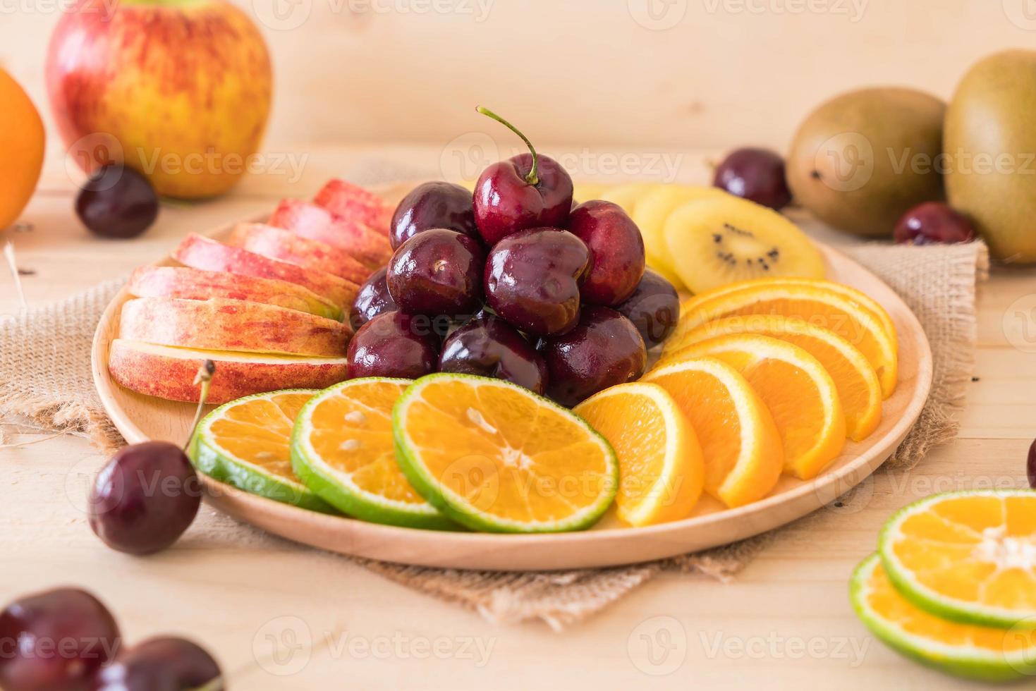 Misto de frutas fatiadas em tigela de madeira foto