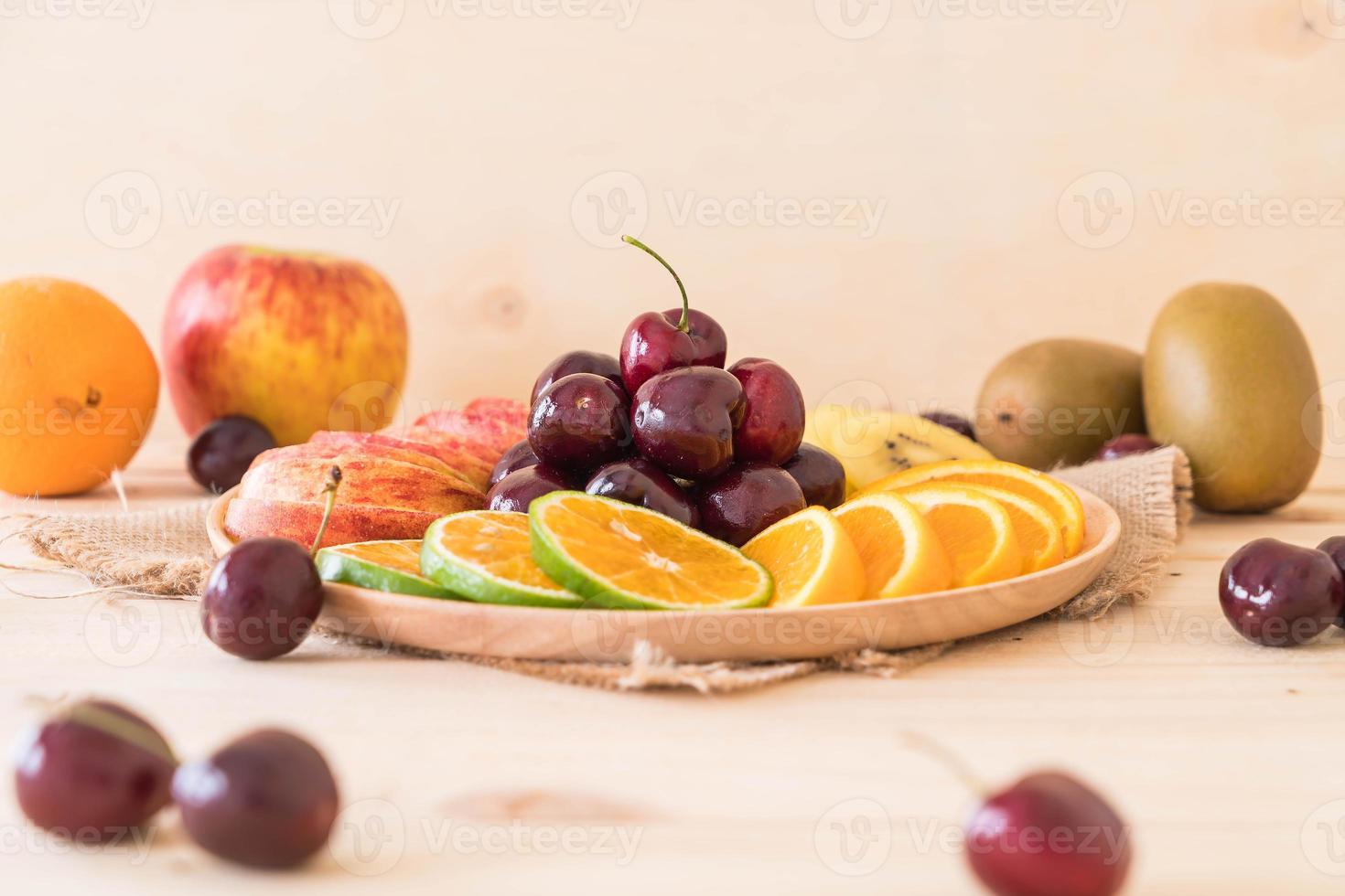 Misto de frutas fatiadas em tigela de madeira foto