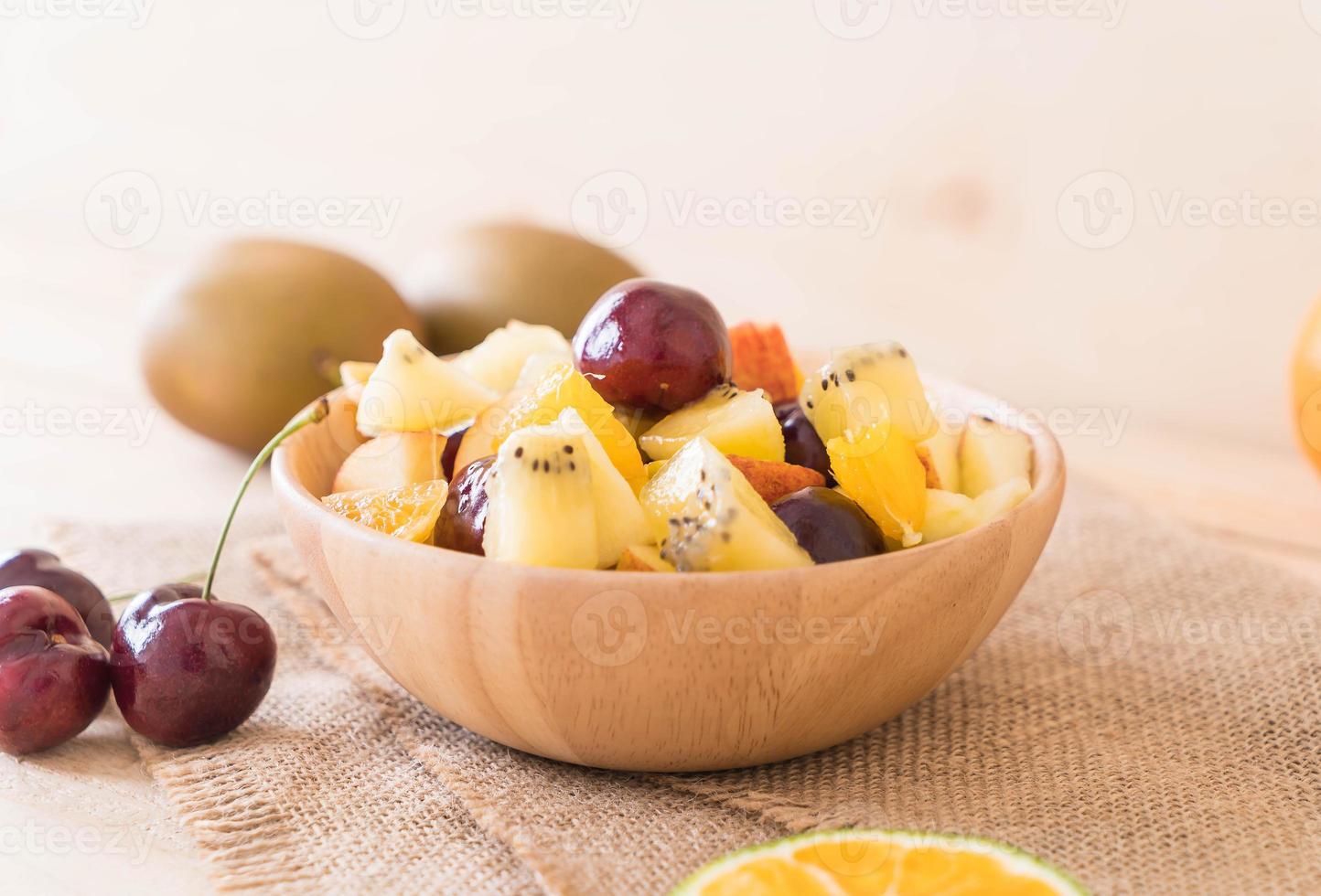 Misto de frutas fatiadas em tigela de madeira foto