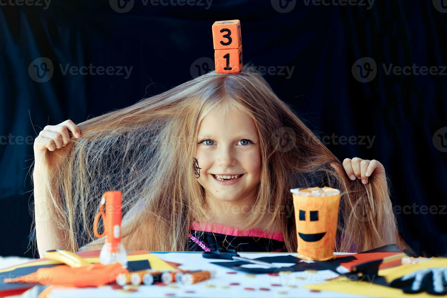 uma pequeno menina é segurando em para dela cabelo e segurando uma de madeira calendário com a encontro do Outubro 31 em dela cabeça. foto