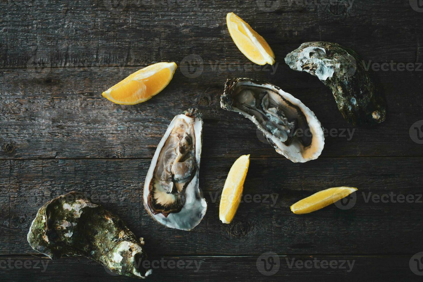 fechar-se do fresco aberto cru ostras com limão e gelo em uma de madeira fundo. saudável frutos do mar. Visão a partir de acima. cópia de espaço. foto