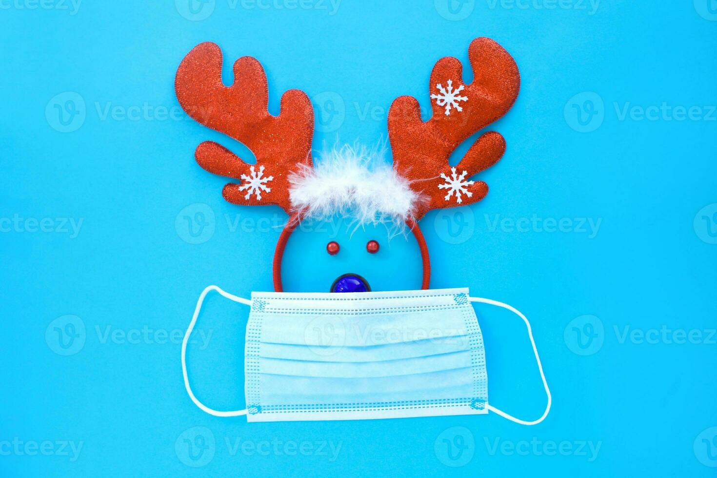 veado face fez a partir de uma veado chifre aro e uma Natal brinquedo dentro uma médico mascarar em uma azul fundo. foto