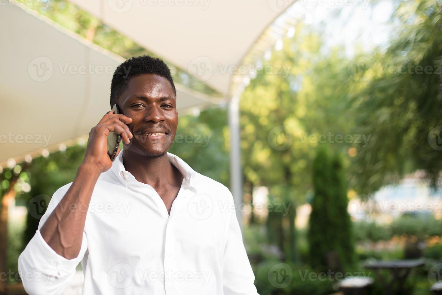 feliz afro-americano com um telefone na rua foto