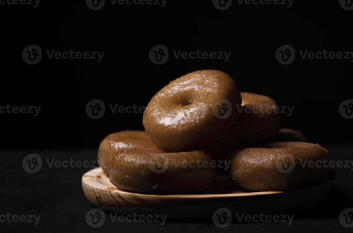 placa de madeira com donuts em um fundo preto foto