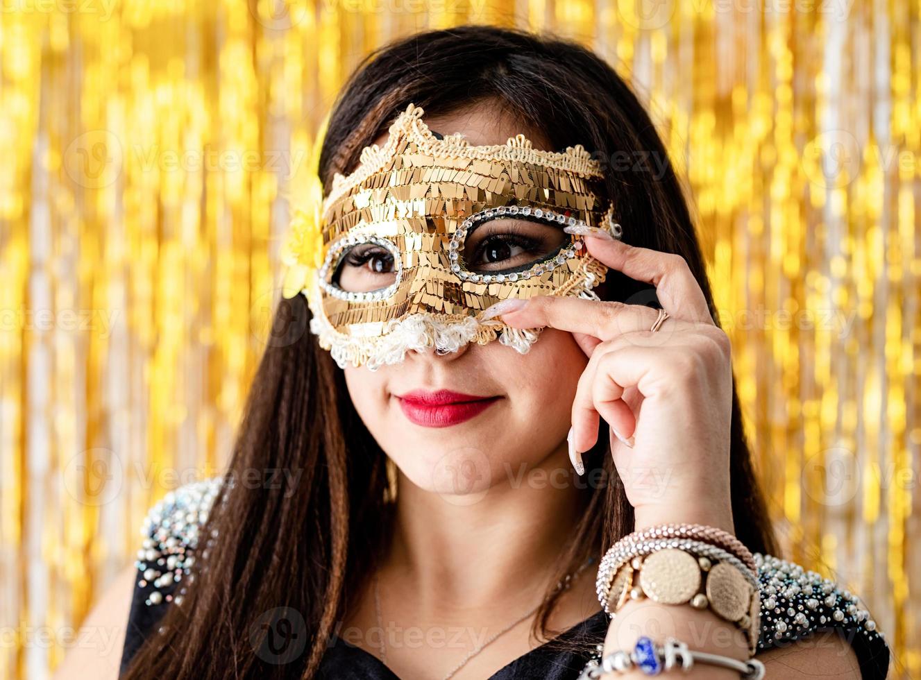 mulher com vestido de festa preto com máscara de baile de máscaras dourada foto