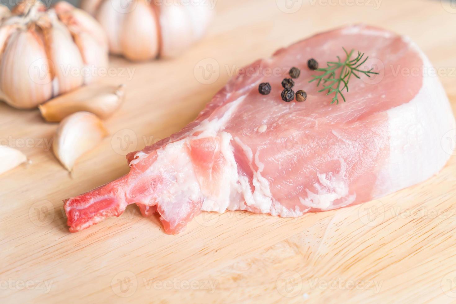 Costeleta de porco fresca na tábua de madeira com alho e pimenta preta foto