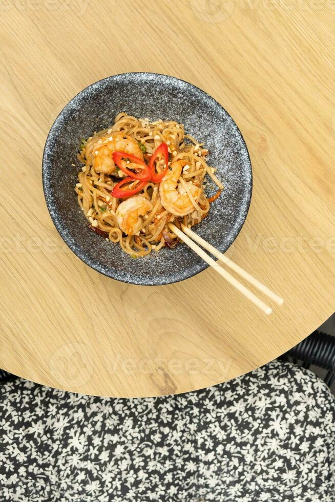 udon Macarrão com camarão e frito legumes dentro uma tigela topo visualizar, plano deitar foto