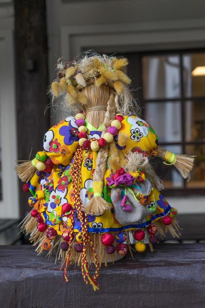 boneca de palha em um terno de pano brilhante feito por mãos humanas foto