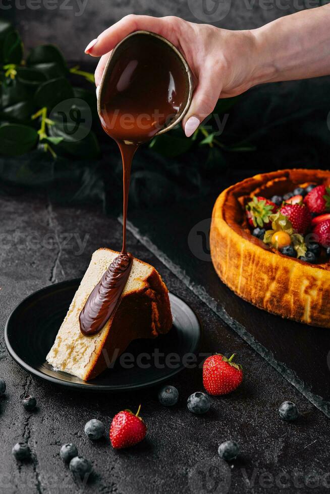 derramando chocolate em delicioso bolo de queijo e bagas foto