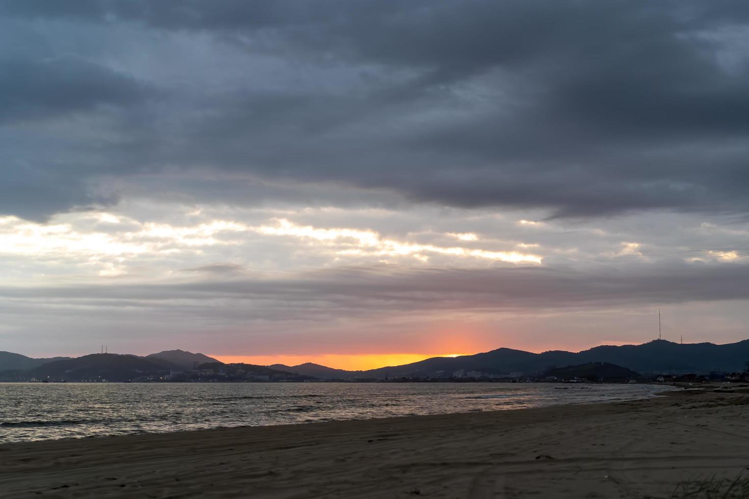 vista do mar com vista para a praia e o pôr do sol. foto